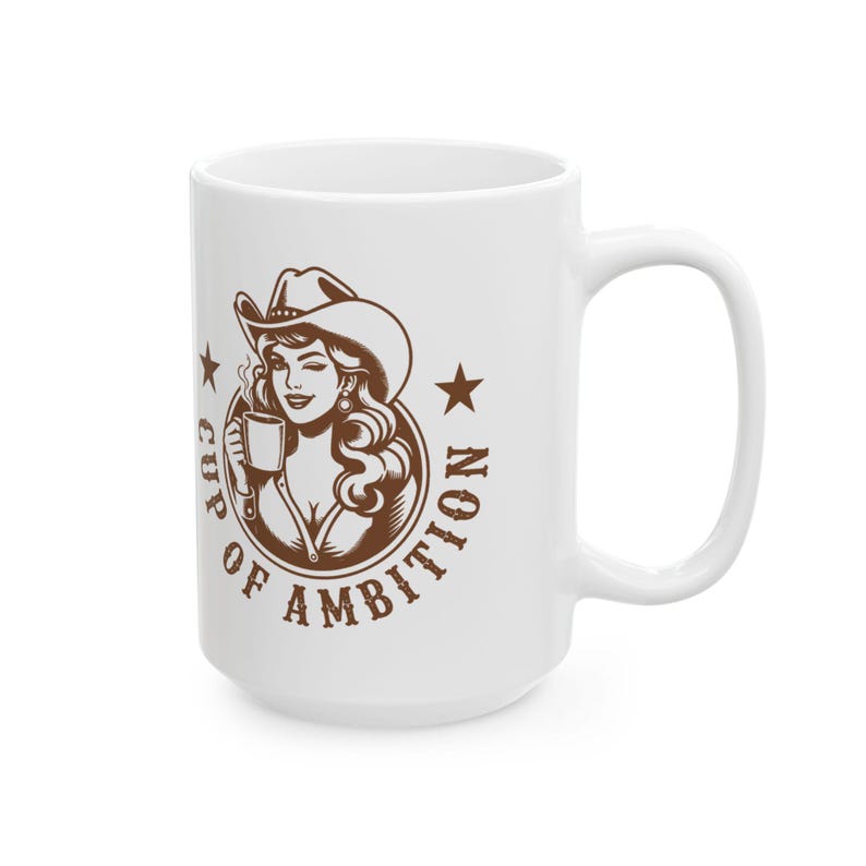 Puede incluir: Una taza de cer&aacute;mica blanca con un gr&aacute;fico marr&oacute;n de una persona con sombrero de vaquero que sostiene una taza peque&ntilde;a. El dise&ntilde;o est&aacute; rodeado por el texto "CUP OF AMBITION" con una estrella a cada lado del marco circular.