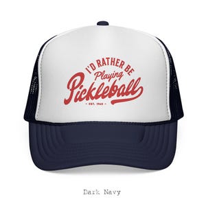 Puede incluir: Gorra de camionero azul marino y blanca con el texto "I'D RATHER BE Playing Pickleball - EST. 1965" en rojo. La gorra tiene una parte trasera de malla y una visera curva. Un accesorio casual para los entusiastas del pickleball.