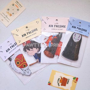 May include: A collection of air fresheners with various anime-style character designs. Each air freshener is packaged in a clear plastic sleeve with a decorative header card. Scents include white musk, jasmine, vanilla, and spirit.