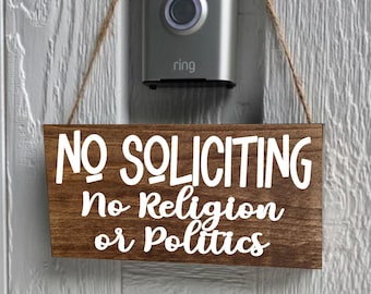 以下が含まれることがあります： ひもで吊るされた「NO SOLICITING No Religion or Politics」と書かれた木製の看板。看板は茶色で文字は白です。