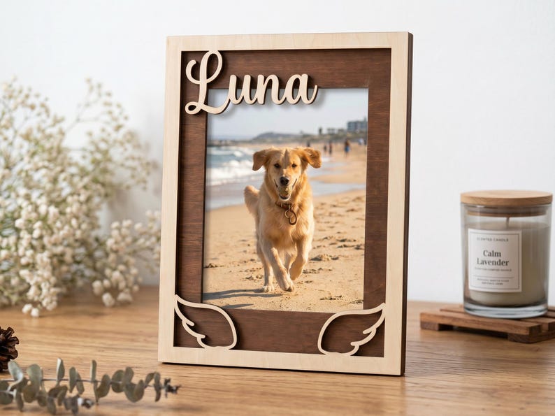 May include: A rectangular wooden picture frame with a dark brown inner border and a light natural wood outer border. The top features the name Luna in cursive script, and the bottom corners have cutout angel wing designs.
