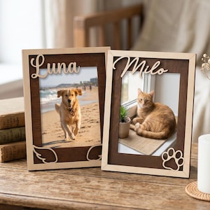 May include: Two rectangular wooden picture frames with light and dark wood tones. The left frame features the name Luna and wing cutouts, holding a photo of a dog. The right frame features the name Milo and a paw print cutout, holding a photo of a cat.