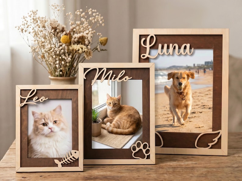 May include: Three rectangular wooden picture frames with dark brown inner borders and light wood outer edges. The frames feature laser-cut names Leo, Milo, and Luna, with decorative accents including a fish skeleton, paw print, and angel wings.