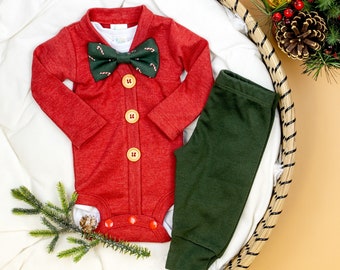 Puede incluir: Mono rojo de manga larga con pajarita de bastón de caramelo y cuatro botones amarillos. Se incluyen pantalones verdes.