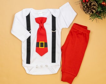 Puede incluir: Un body blanco con tirantes negros y una corbata de lazo roja con un cinturón negro. El body tiene broches a presión en la entrepierna. El atuendo se combina con pantalones rojos.