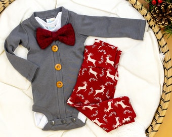 Puede incluir: Un body gris de manga larga con una pajarita roja y botones de madera. El body se combina con leggings rojos y blancos con estampado de renos.