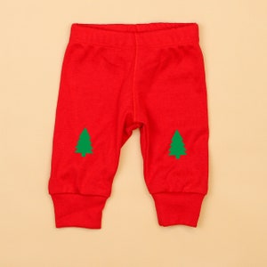 May include: Red baby leggings with green Christmas tree designs on the knees.