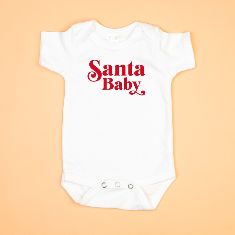 May include: White baby onesie with red text that says "Santa Baby".