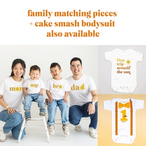 May include: A family of four wearing matching white t-shirts with a sun and text that says "mon", "one", "bro", and "dad". The image also shows two baby onesies, one with the text "First trip around the sun" and the other with a number one and the text "Oliver".