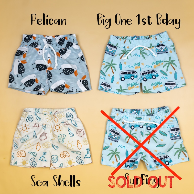 May include: Four pairs of toddler swim trunks with different patterns. The patterns include pelicans, sea shells, and a blue van with the words "The Big One" on it. One pair of swim trunks is marked "Sold Out".