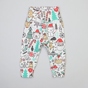 May include: White baby leggings with a Christmas-themed print featuring a variety of festive icons, including a snowman, Santa Claus, reindeer, candy canes, and Christmas trees.
