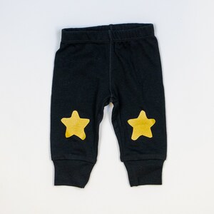 Puede incluir: Leggings negros para beb&eacute; con detalles de estrellas doradas en las rodillas.