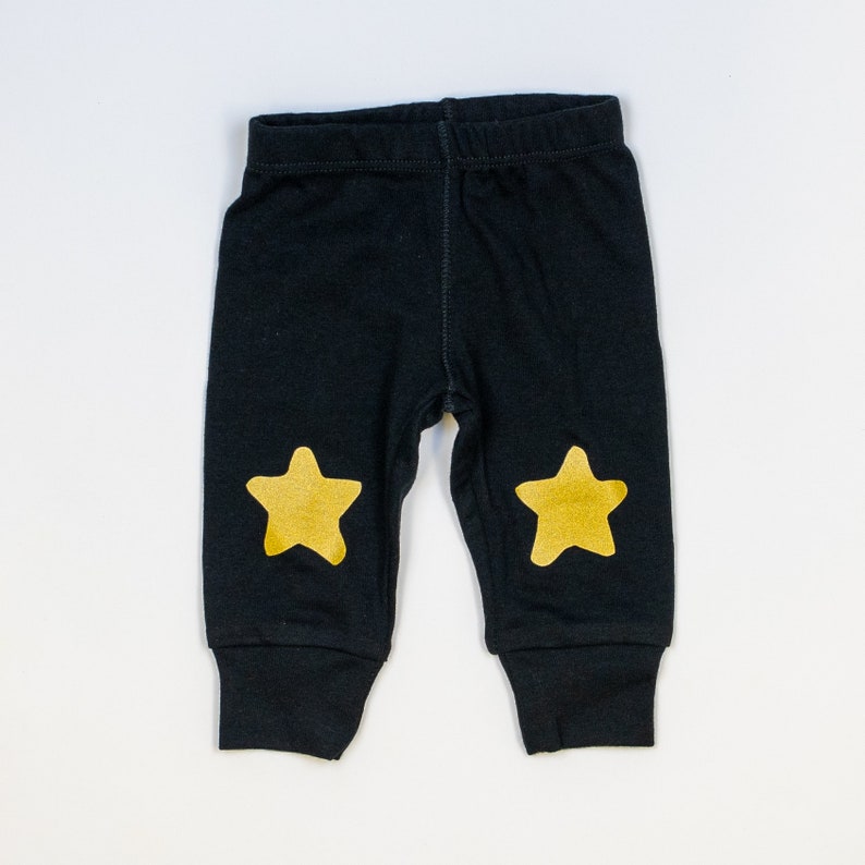 Puede incluir: Leggings negros para beb&eacute; con detalles de estrellas doradas en las rodillas.