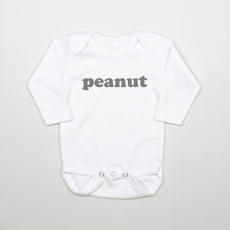 May include: White long-sleeve baby onesie with the word "peanut" printed in gray on the front.