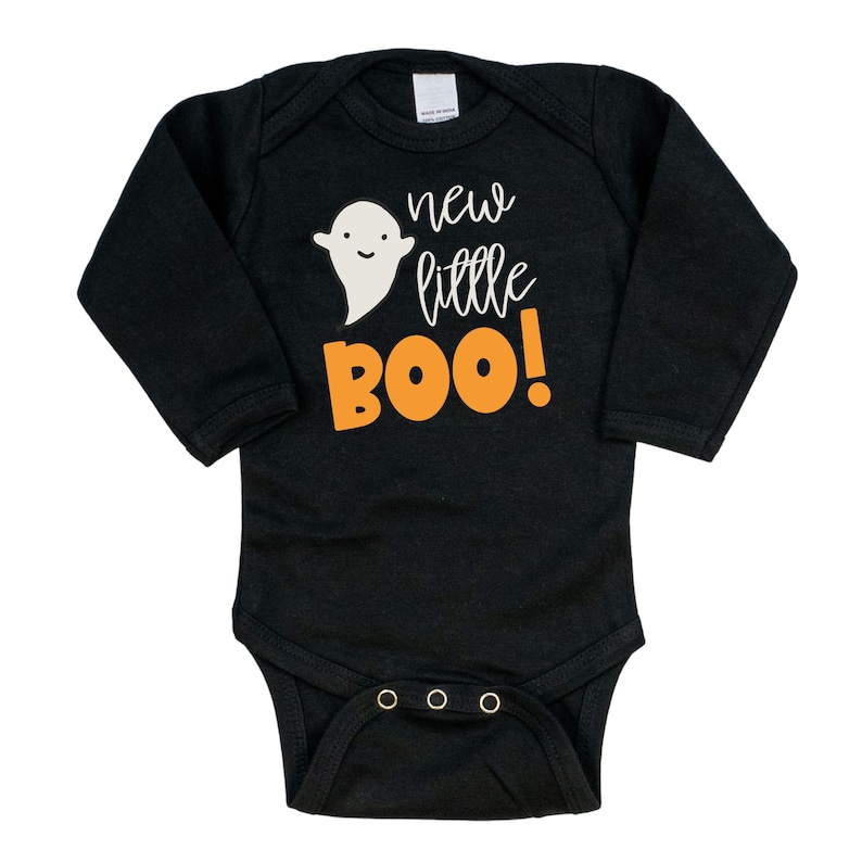 Pu&ograve; includere: Body da neonato a maniche lunghe nero con un fantasma bianco e testo arancione che dice "new little BOO!"