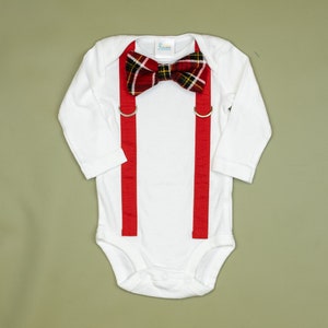 May include: White long-sleeve bodysuit with red suspenders and a red and black plaid bow tie.