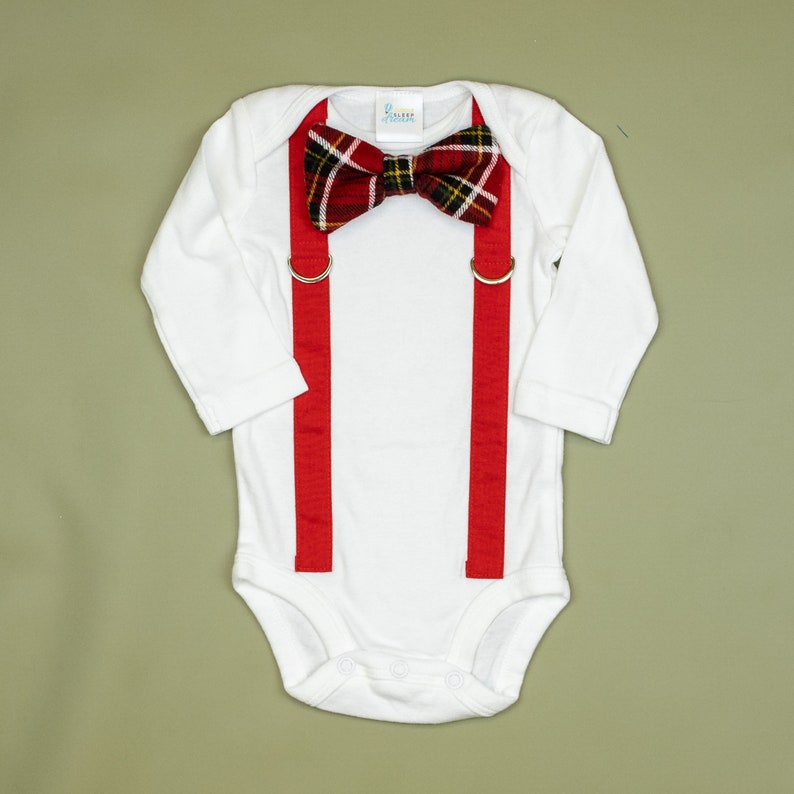 May include: White long-sleeve bodysuit with red suspenders and a red and black plaid bow tie.