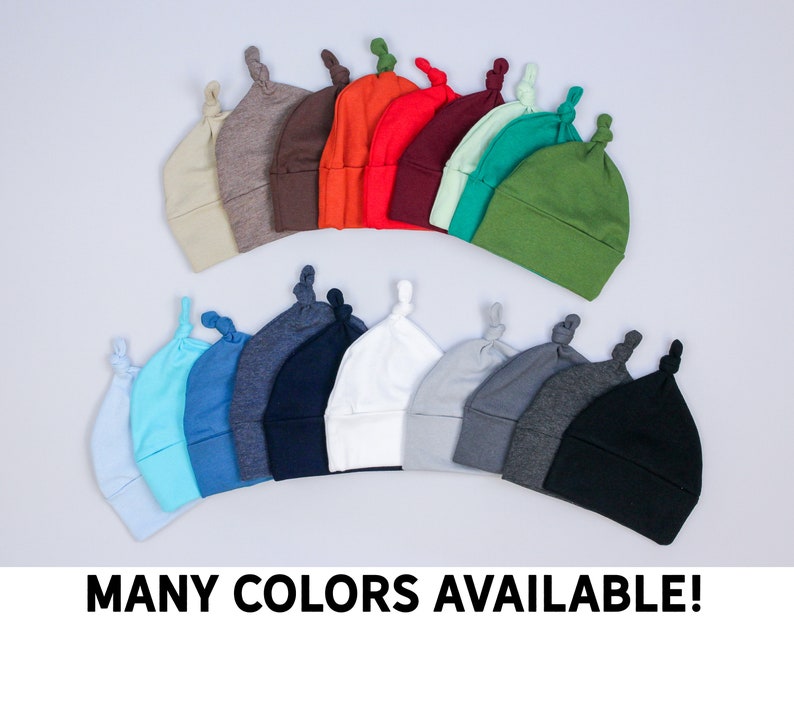 May include: A selection of baby knot hats in a variety of colours, such as beige, brown, orange, red, teal, green, light blue, blue, navy, white, grey, dark grey, and black. The text "MANY COLORS AVAILABLE!" is displayed at the bottom.