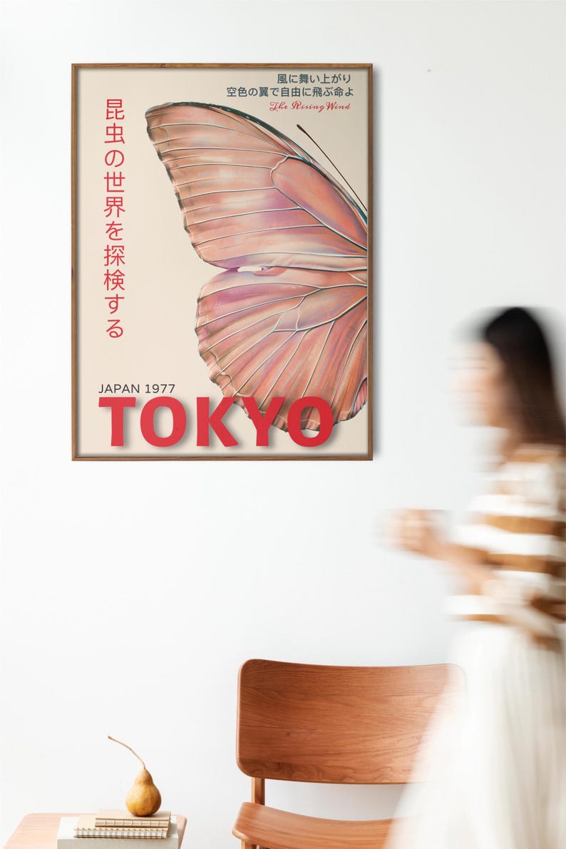 May include: A vintage poster with a butterfly wing design in shades of pink and orange. The poster has the text "昆虫の世界を探検する" in Japanese, which translates to "Explore the world of insects." The poster also has the text "The Rising Wind" and "JAPAN 1977 TOKYO" in red.