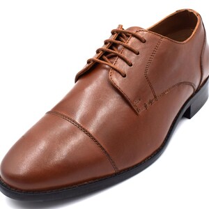 May include: A pair of brown leather lace-up shoes with a cap toe design.