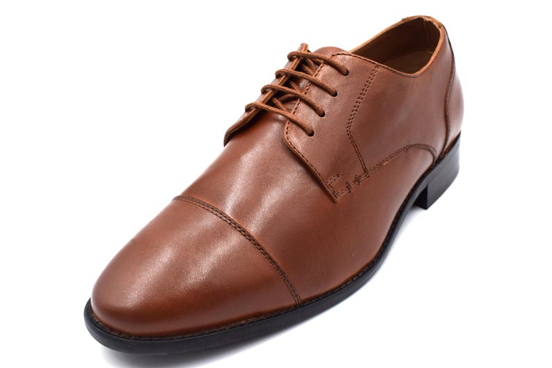 May include: A pair of brown leather lace-up shoes with a cap toe design.
