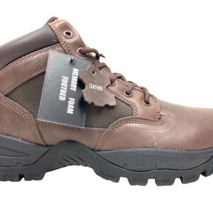 K&ouml;nnte beinhalten: Braune Lederstiefel mit Schn&uuml;rung und Memory-Schaum-Fu&szlig;bett. Die Stiefel haben eine robuste Au&szlig;ensohle und ein Etikett mit der Aufschrift "Leder" und "Memory Foam Fu&szlig;bett".