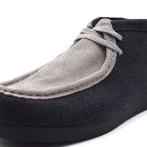 May include: A pair of black and gray suede casual shoes with a lace-up closure.