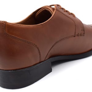 May include: Brown leather lace-up oxford shoes with a closed toe and a black rubber sole.
