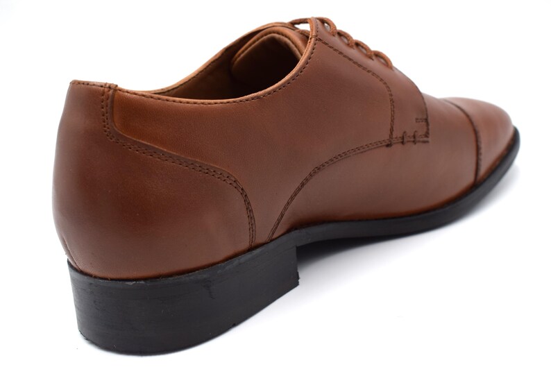 May include: Brown leather lace-up oxford shoes with a closed toe and a black rubber sole.