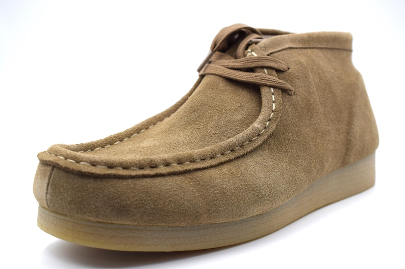 May include: A pair of brown suede ankle boots with a lace-up closure and a stitched seam around the toe.