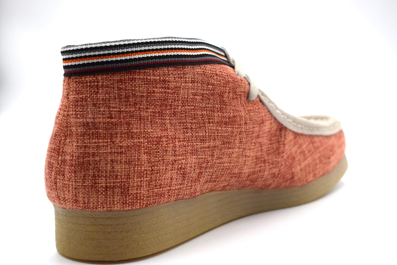 May include: A pair of red canvas shoes with a brown sole and a black and white striped trim around the top.