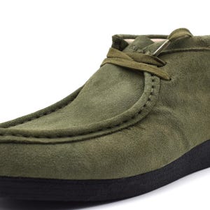 May include: A pair of green suede ankle boots with a lace-up closure and a black rubber sole.