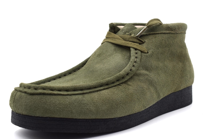 May include: A pair of green suede ankle boots with a lace-up closure and a black rubber sole.