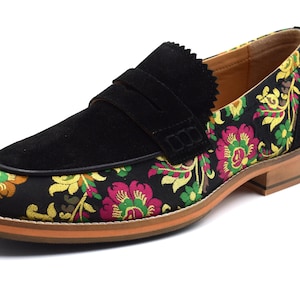 May include: Black suede loafers with a floral patterned fabric toe. The fabric is a mix of pink, yellow, green, and brown.