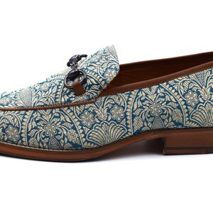 Pode incluir: Sapatos de mocassins azuis e dourados com sola de couro marrom e fivela de metal prateado.