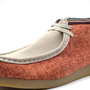 May include: Orange and beige casual shoes with a suede toe and a fabric upper. The shoes have a lace-up closure and a brown rubber sole.