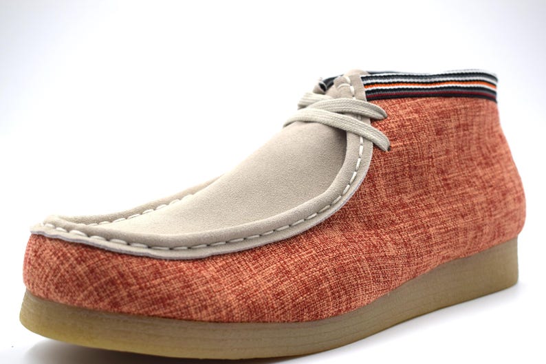 May include: Orange and beige casual shoes with a suede toe and a fabric upper. The shoes have a lace-up closure and a brown rubber sole.