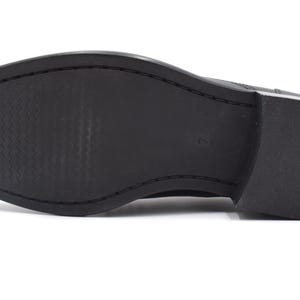 May include: The bottom of a black leather shoe with a textured sole.