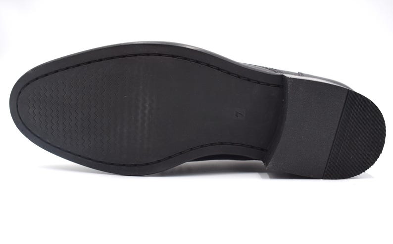 May include: The bottom of a black leather shoe with a textured sole.