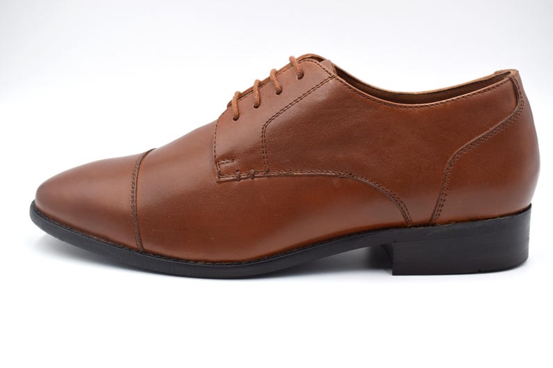 May include: A pair of brown leather lace-up shoes with a cap toe.