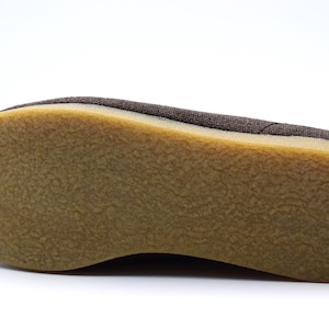 May include: Close-up of the bottom of a brown canvas shoe with a brown rubber sole.
