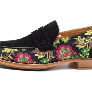 May include: Black suede loafers with a floral pattern on the front and a brown leather sole.