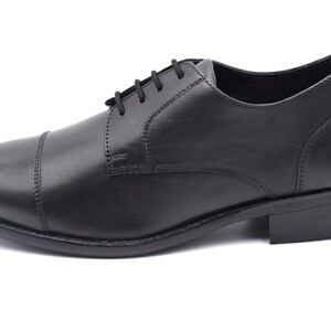 May include: Black leather lace-up dress shoes with a cap toe.