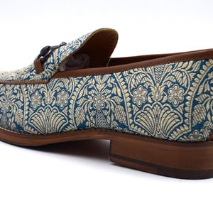Pode incluir: Sapatos de mocassim azuis e dourados com sola de couro marrom e fivela decorativa.