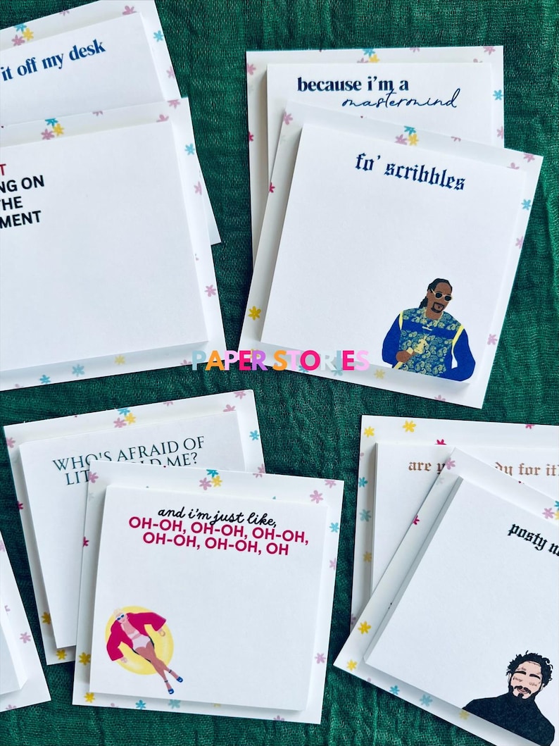 May include: A set of colorful sticky note pads with various quotes and illustrations. The quotes include "it off my desk", "because I'm a mastermind fo' scribbles", "WHO'S AFRAID OF LIT D.ME?", and "and I'm just like, OH-OH, OH-OH, OH-OH, OH-OH, OH-OH, OH". The illustrations include a cartoon of a person in a pool float, a cartoon of a person with a microphone, and a cartoon of a person with a crown.