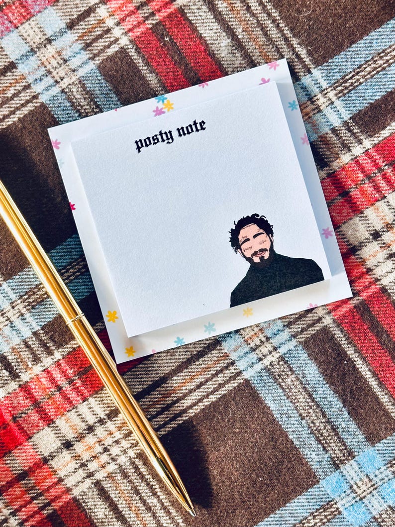 May include: A white sticky note pad with a colorful floral border. The text "Posty Note" is printed in black at the top of the pad. A black and white illustration of a man with a beard is printed on the pad.