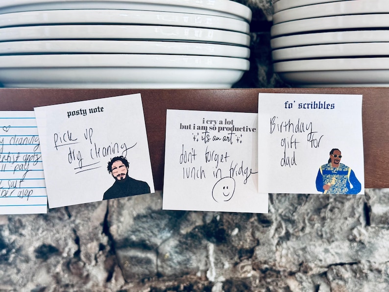 May include: Three sticky notes with handwritten messages and cartoon images. The first note says "Pick up dry cleaning". The second note says "I cry a lot but I am so productive it's an art". The third note says "Birthday gift for dad".