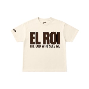 以下が含まれることがあります： 100%コットン素材のクリーム色のクロップドTシャツ。フロントにはダークブラウンのテキストで「EL ROI THE GOD WHO SEES ME」とプリントされています。右袖には小さなロゴがあり、首元の内側のラベルには「POWER OF PRAISE」と記されています。