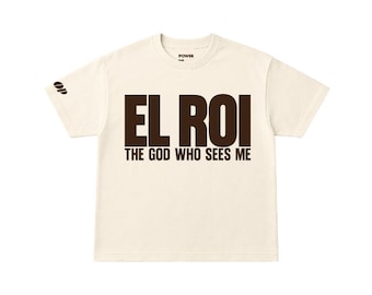 May include: A cream-colored cropped t-shirt made of 7.5 oz 100% cotton. The front features the dark brown text EL ROI THE GOD WHO SEES ME. A small logo is printed on the right sleeve, and the inner neck label reads POWER OF PRAISE.