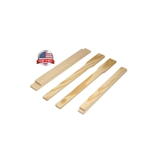May include: Four unfinished wooden pieces, including two with paddle-like shapes, and two rectangular pieces. The pieces are light-colored and appear to be new. A "Made in USA" sticker is in the upper left corner.
